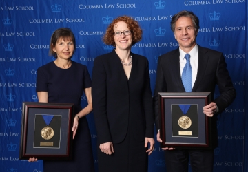Alison S. Ressler '83 and Antony Blinken '88 hold up their Medal for Excellence awards with Dean Gillian Lester