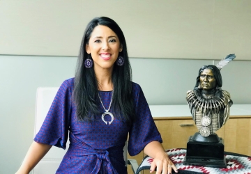 Woman in purple dress next to bust of Native American leader
