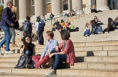 Students sit on the steps of Low Library on a sunny day