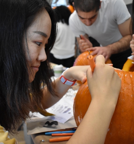A student carves a pumpkin.