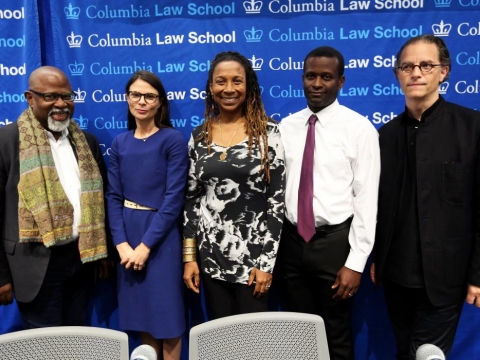 Five Columbia Law professors standing in front of a blue backdrop with the words Columbia Law School repeated many times