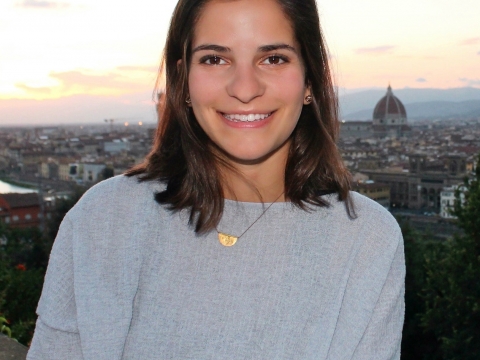 Columbia Law School graduate Emma DiNapoli ’20 in a pale gray sweater with clouds behind her