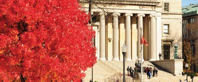 A red autumn tree in front of the Low Library steps.
