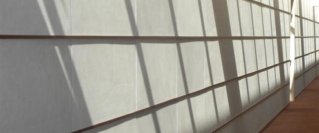 A hallway in Jerome Greene Hall has the shadows of a grid of windows on the wall.
