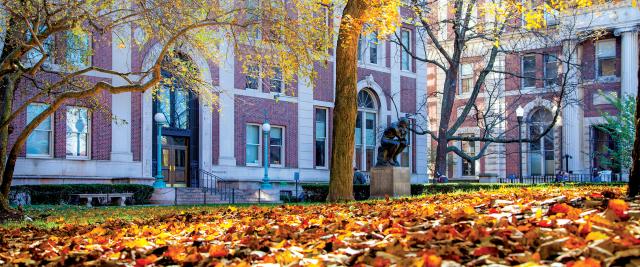 The Thinker statue surrounded by autumn leaves