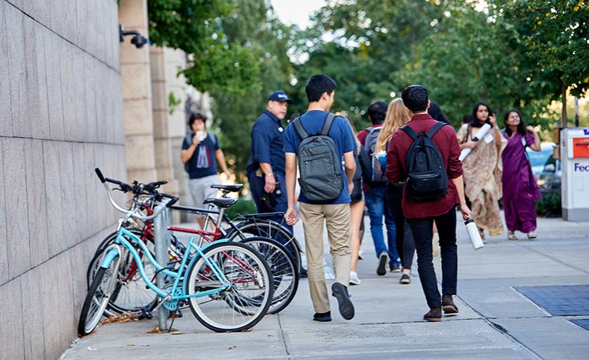 Students walk by a bike rack in front of Jerome Greene Hall