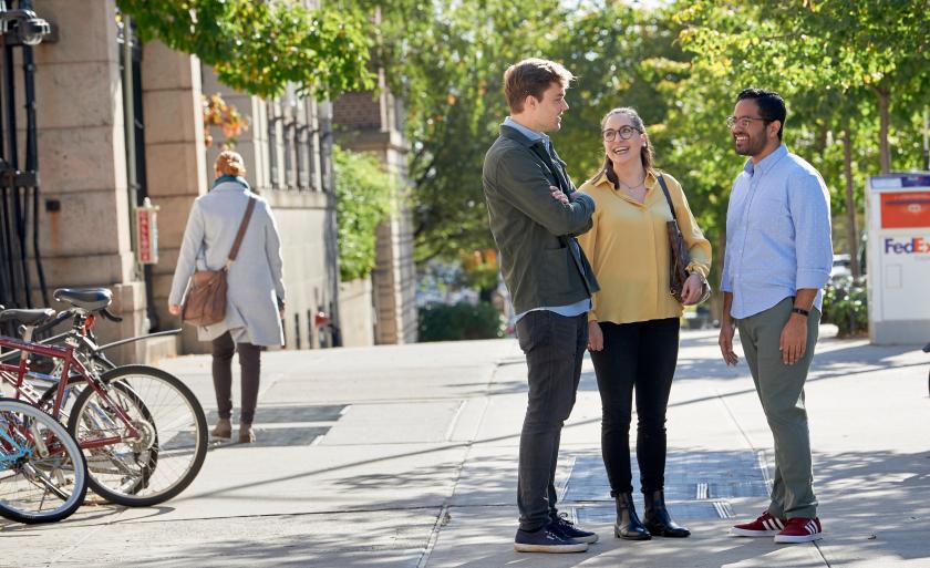 Three students talk on 116th Street