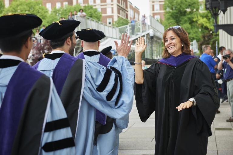Dean Sylvia Polo high fives graduating students.