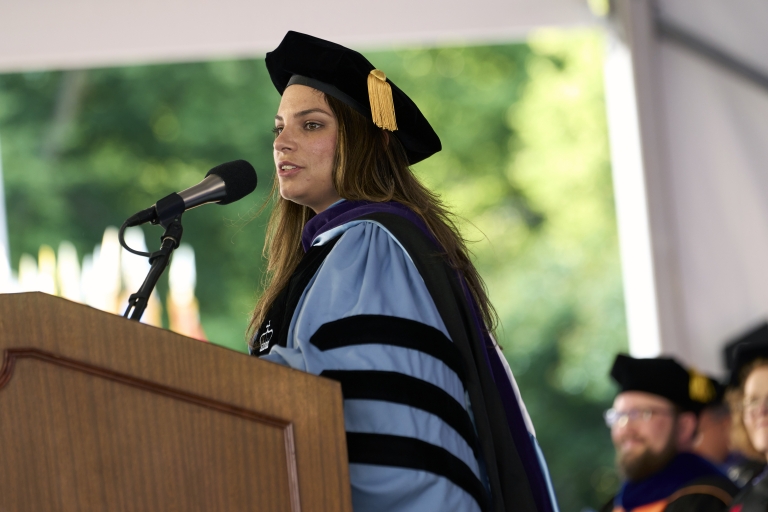 Woman in graduation regalia at podium