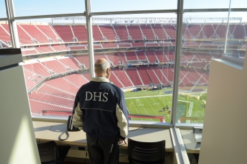 Man in DHS jacket looks over empty football stadium