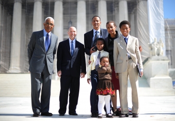 Group shot of three men, one woman, three children on the steps of the Supreme Court