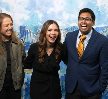 Two women and a man in front of a painted mural