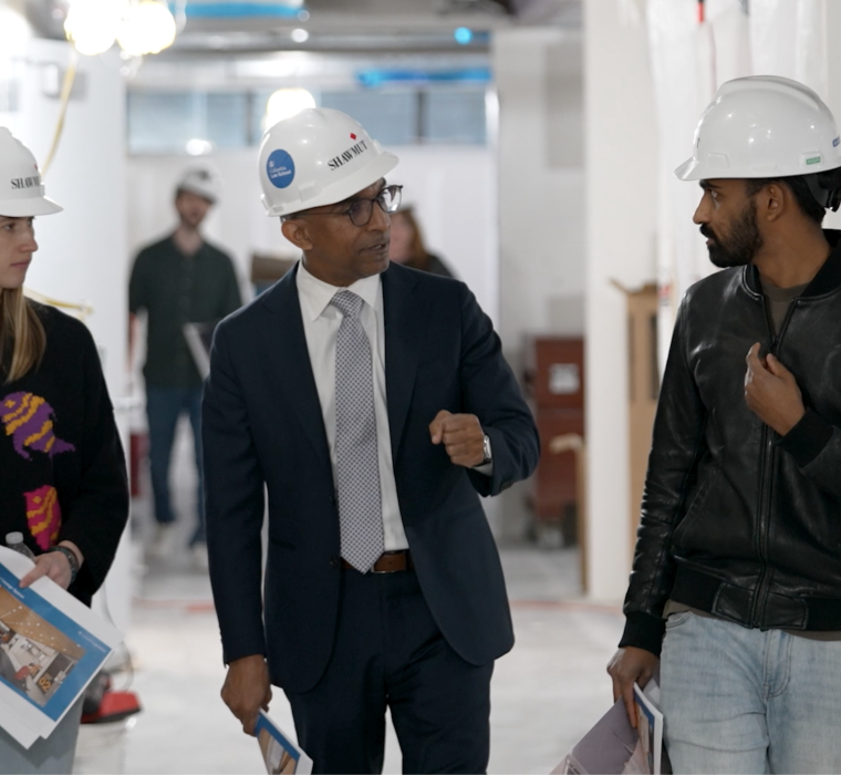 Two. men and a woman in hardhats walking and talking
