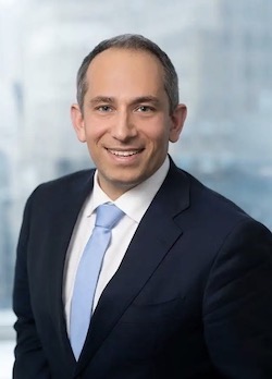 Man in dark jacket, blue tie and white shirt