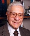 Head shot of man with white hair and glasses