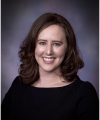 Caitlin McGrail, a smiling white woman with brown hair and a black shirt.