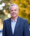 Professor Conrad Johnson stands in front of autumn trees on the Columbia campus.