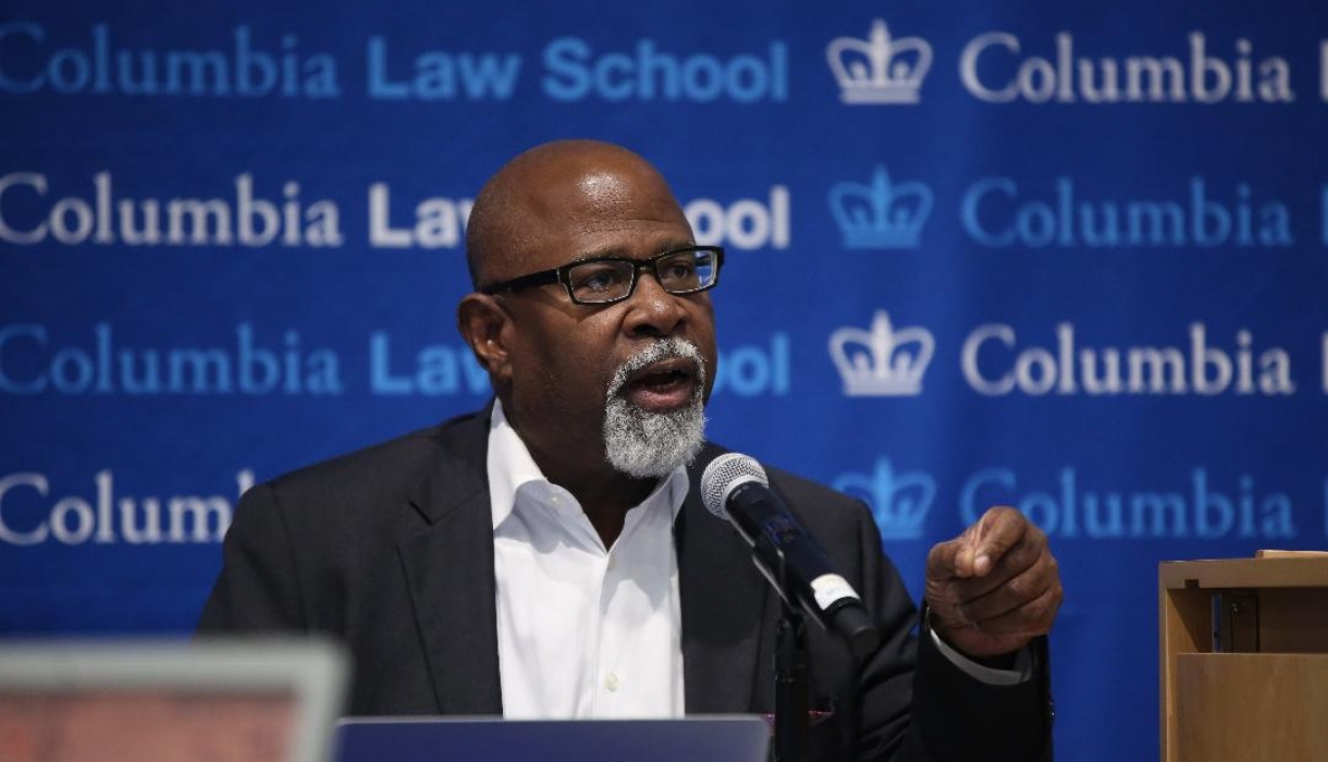 Columbia Law Professor Kendall Thomas in glasses and white shirt in front of mircrophone