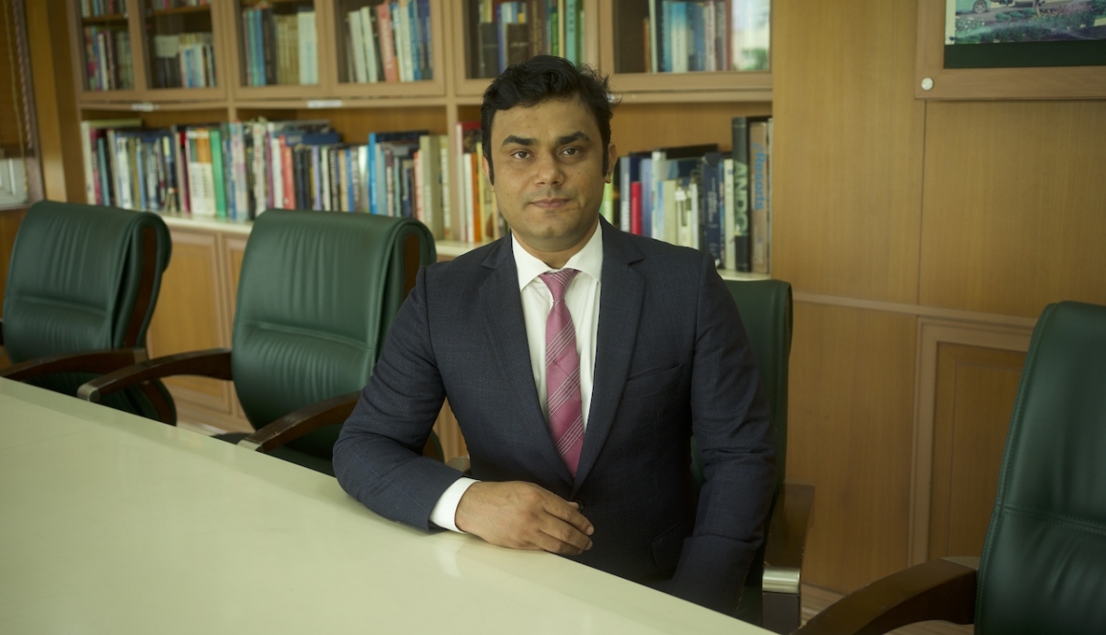 Bhagwati Fellow Devranjan Mishra in suit and tie sitting at conference table