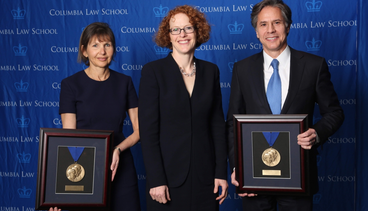 Alison S. Ressler '83 and Antony Blinken '88 hold up their Medal for Excellence awards with Dean Gillian Lester