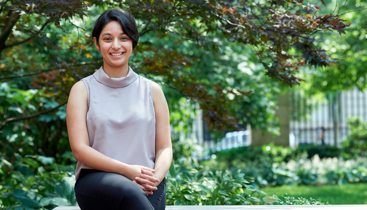 Bhagwati Fellow Sparsha Janardhan sits on a bench outside Jerome Greene Hall