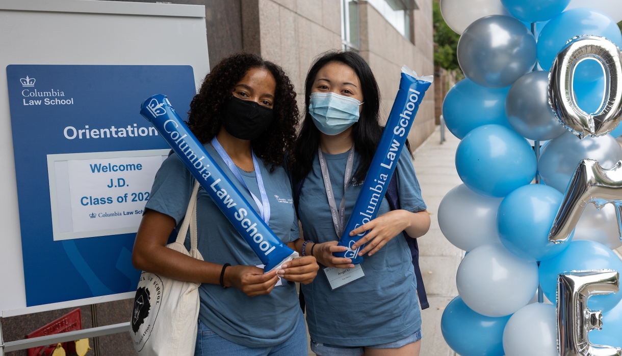 Two women in blue shirts next to blue and white balloons