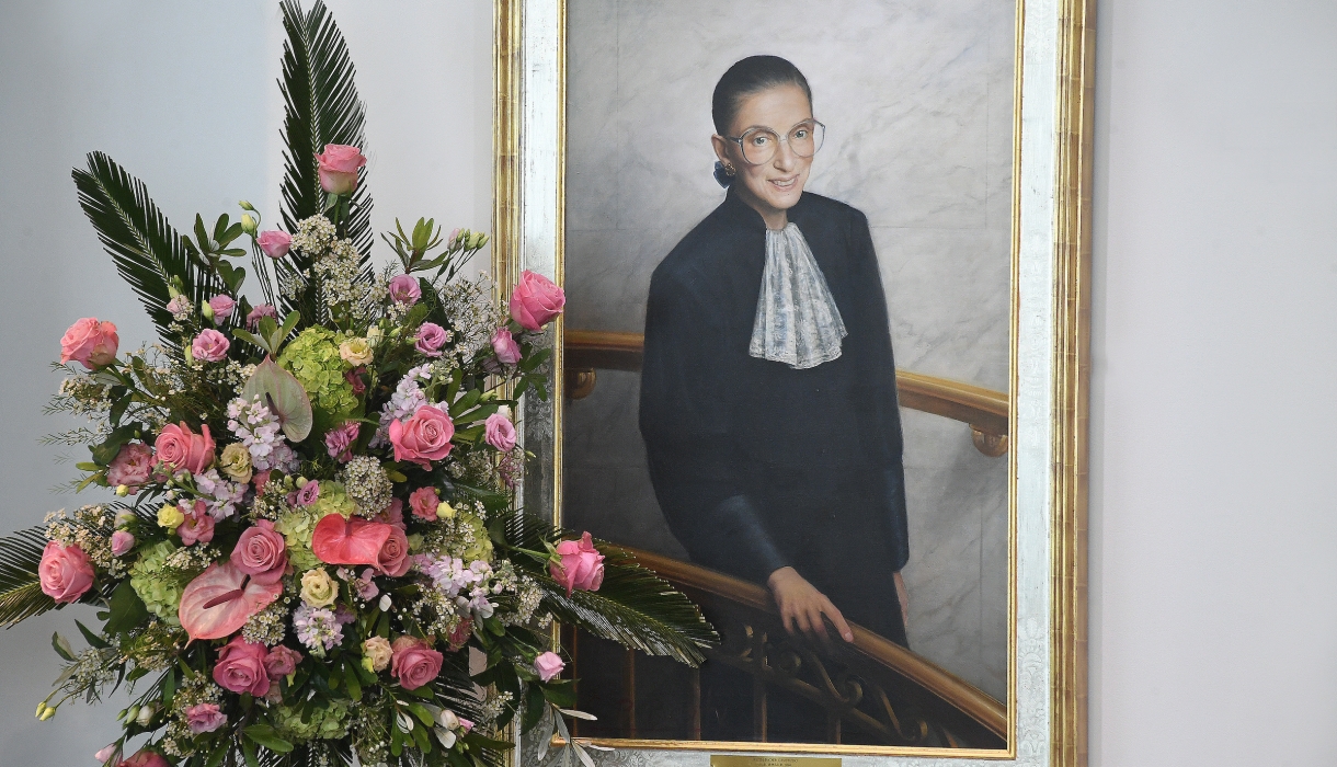 Flowers in front of a portrait of Ruth Bader Ginsburg.