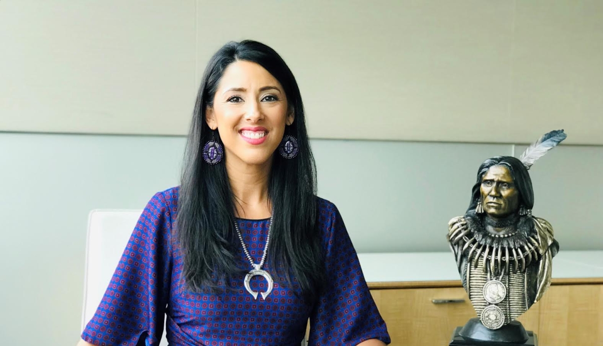 Woman in purple dress next to bust of Native American leader