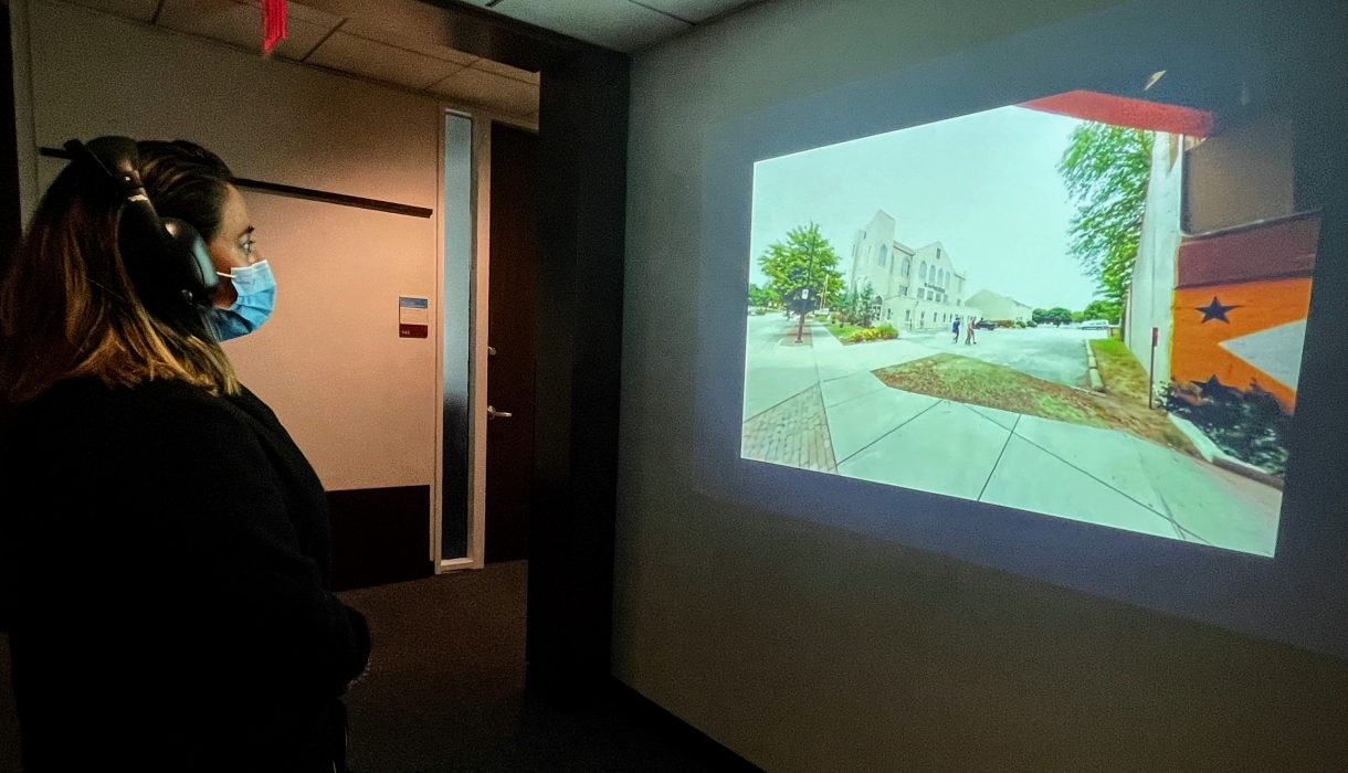 A woman wearing headphones looking at an image on a wall