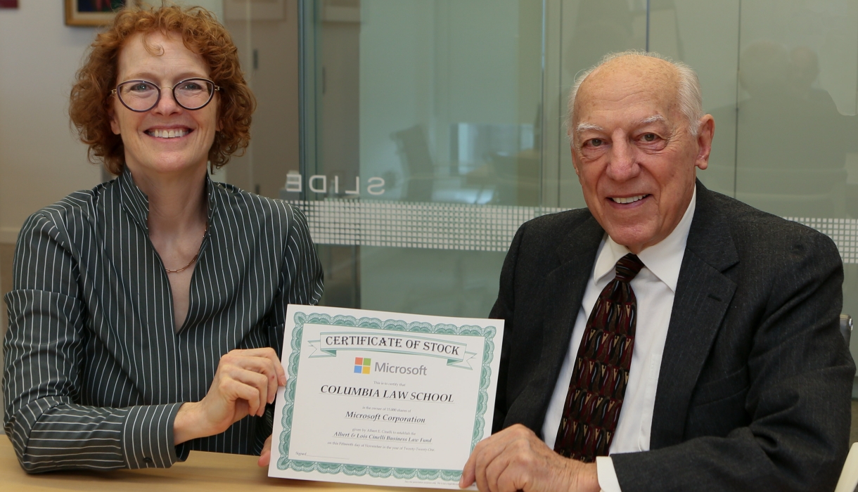 Woman and man, seated side by side, hold stock certificate