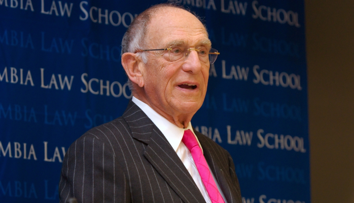 Man with glasses in pinstripe suit and pink tie