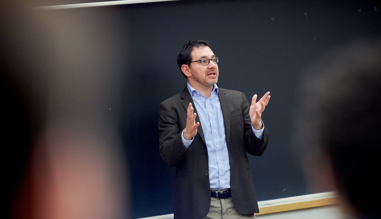 Dark haired man speaking and gesturing 