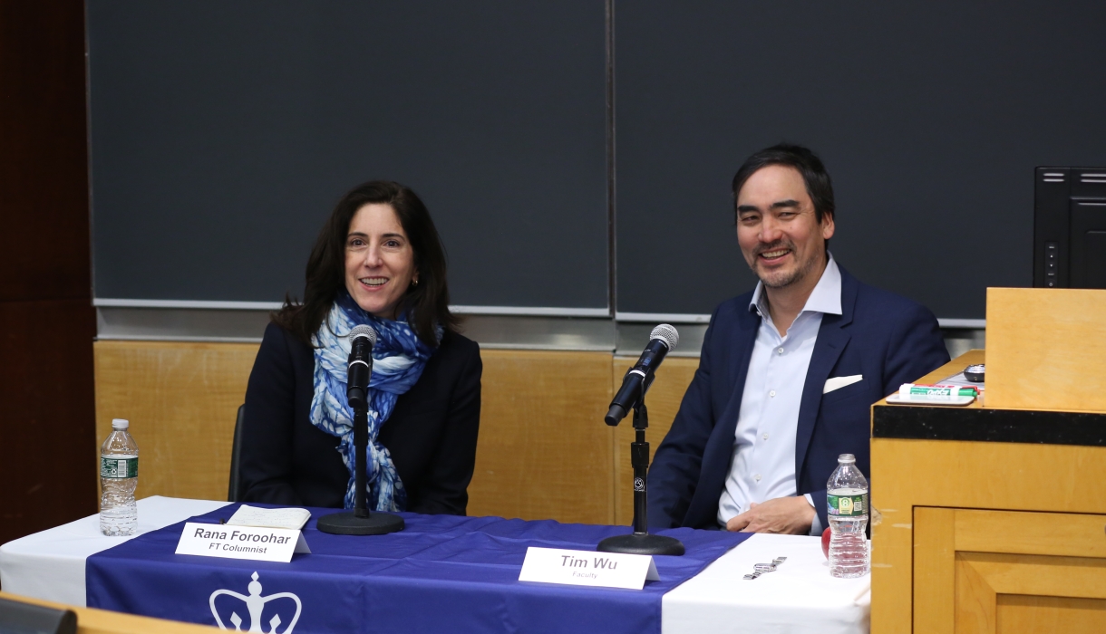 Woman and man sitting at panel table, smiling. 