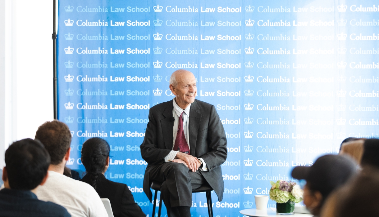 Man in suit in front of Columbia Law School banner