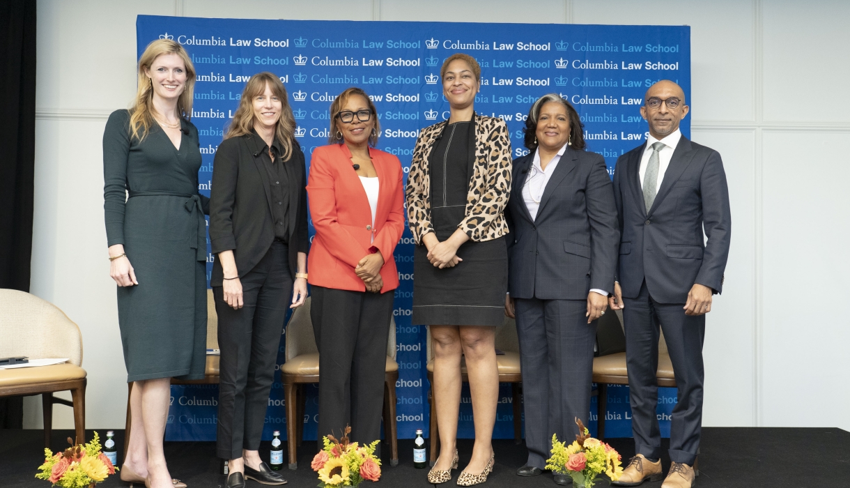 Lineup of five women and a man in professional attire, on a dais.