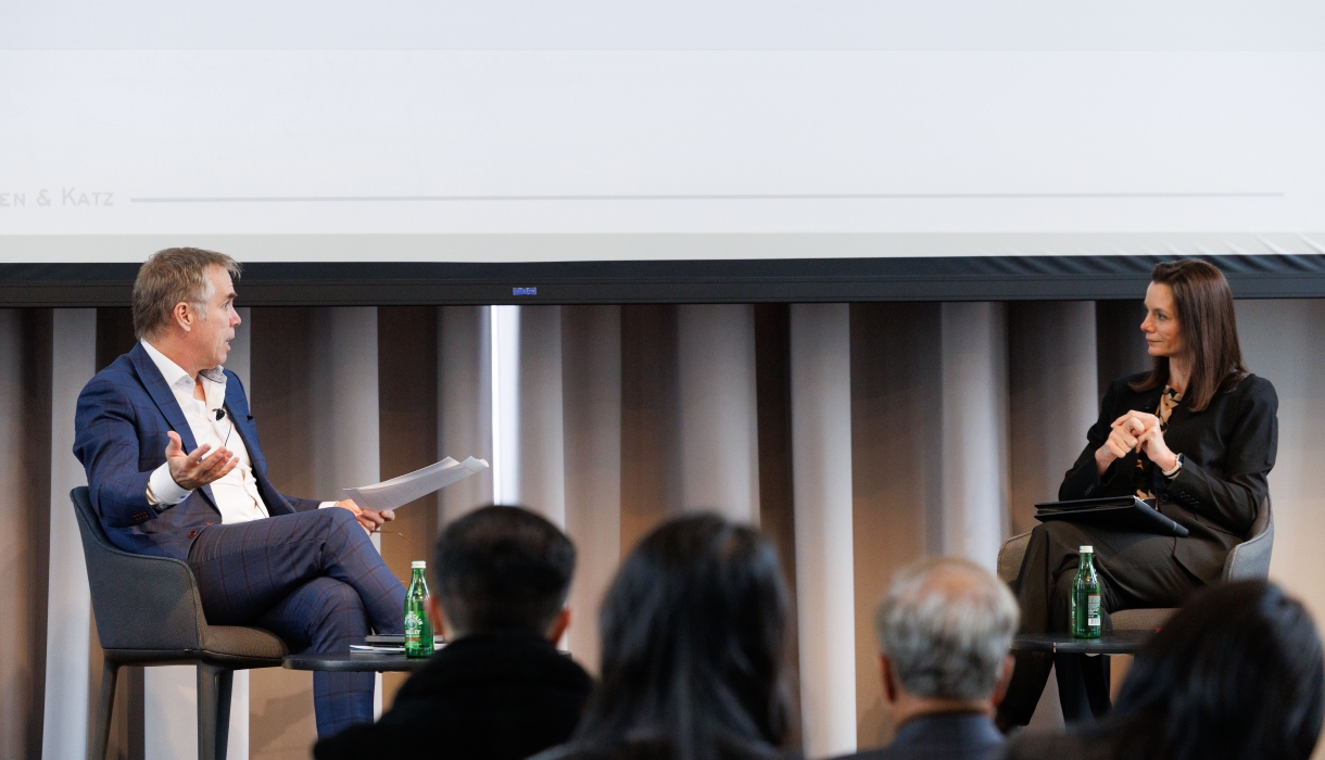 Man interviewing woman, both seated onstage