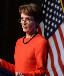Sarah Cleveland standing at a podium in front of an American flag