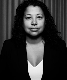 Pictured above is a black and white photo of Alice Fontier. She has long curly hair dark hair. She is wearing a dark blazer and white top. 