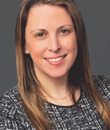 Pictured above is Lucy Kweskin. She is smiling, has long auburn hair and hazel eyes. 