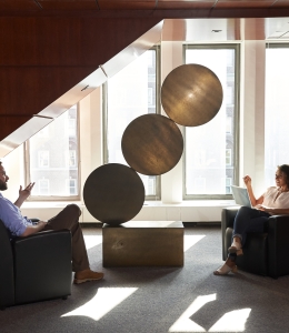 Two students sit apart in a sunlit area talking