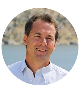 Photo of Steve Bullock in button down shirt in front of water.