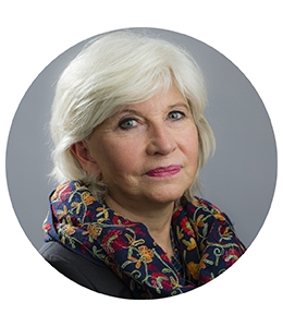 Portrait of Laurence Tubiana, with white hair and floral scarf.