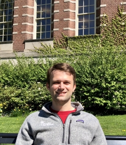 Student in gray jacket in front of brick building