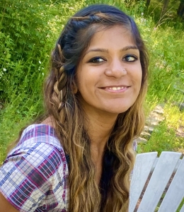 Image of a woman smiling and wearing a multi-colored shirt