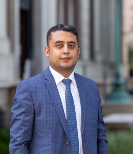 Man in a blue blazer, white shirt, and blue tie