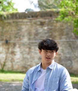 Young man in blue shirt sitting outside