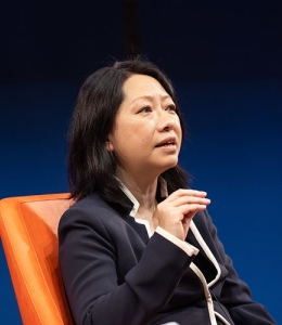 Woman speaking while seated in a chair onstage