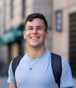 Man in t-shirt and necklace standing outdoors