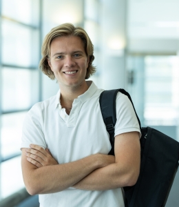 Man in white polo shirt with bag over his shoulder