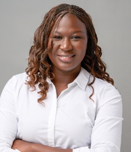 Woman with long wavy hair wearing white shirt smiling. 